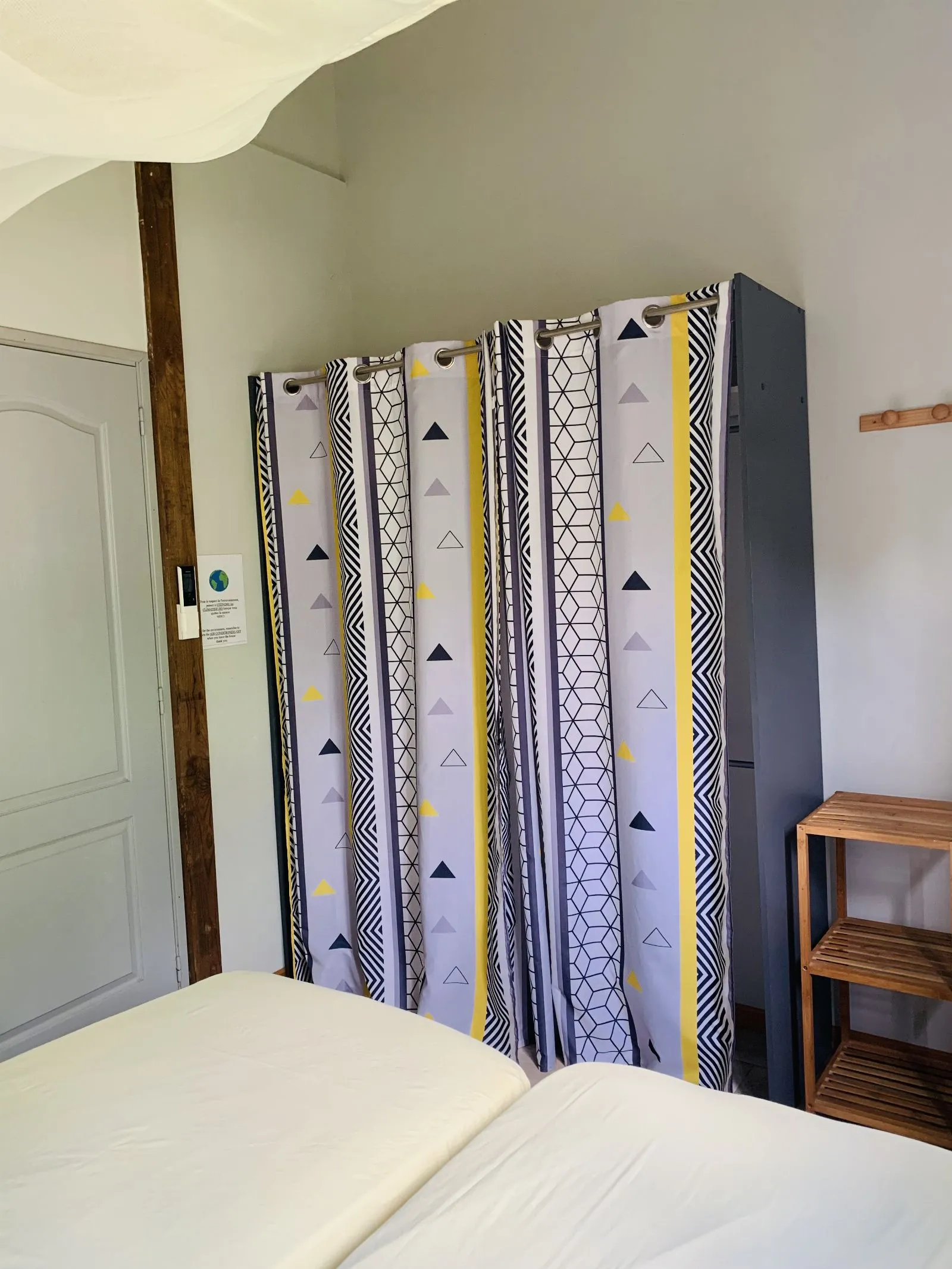 Rideau à motif graphique séparant la chambre, avec étagère en bois à côté