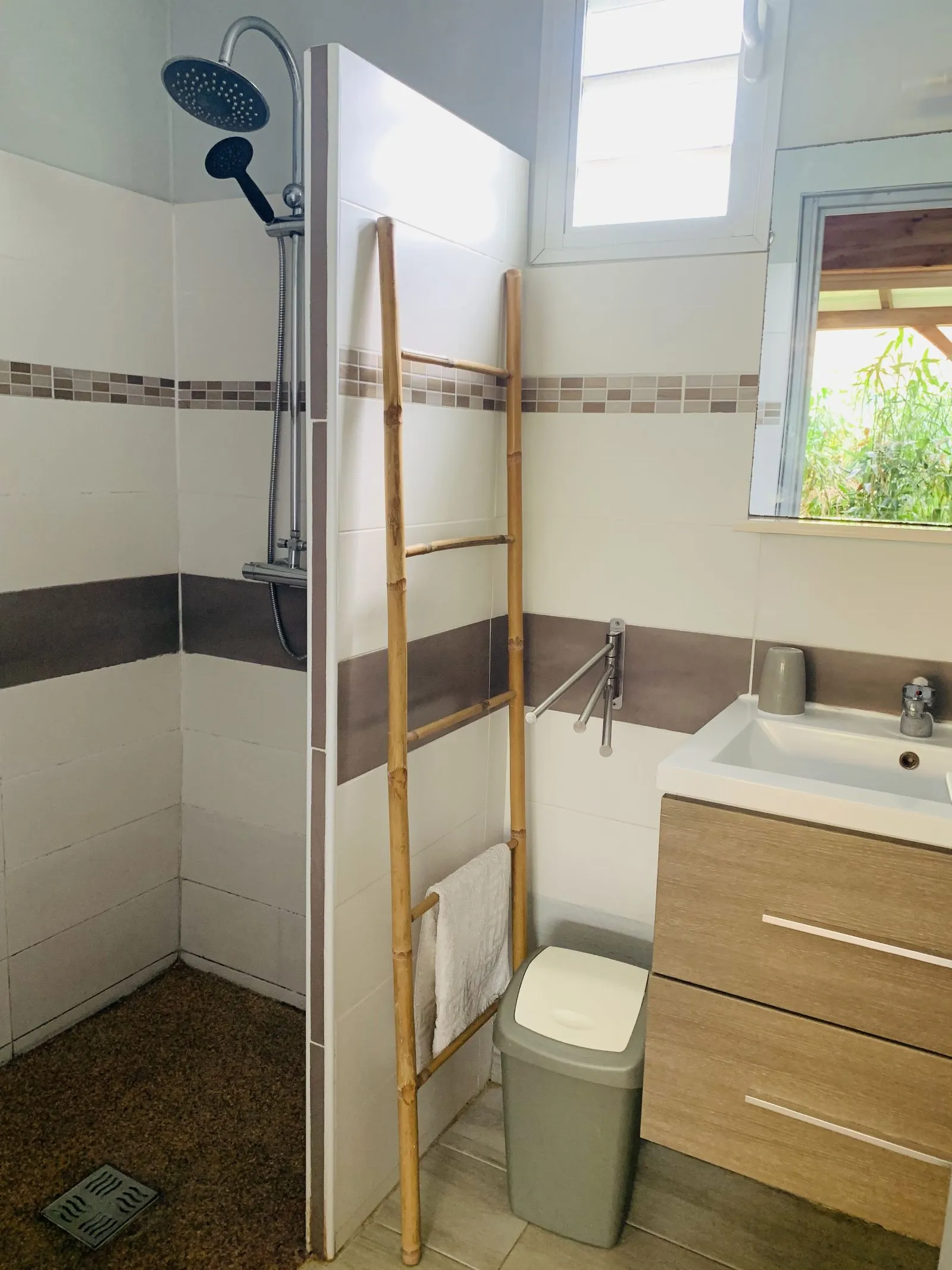 Salle d’eau avec douche à l’italienne, vasque et échelle de bambou porte-serviettes