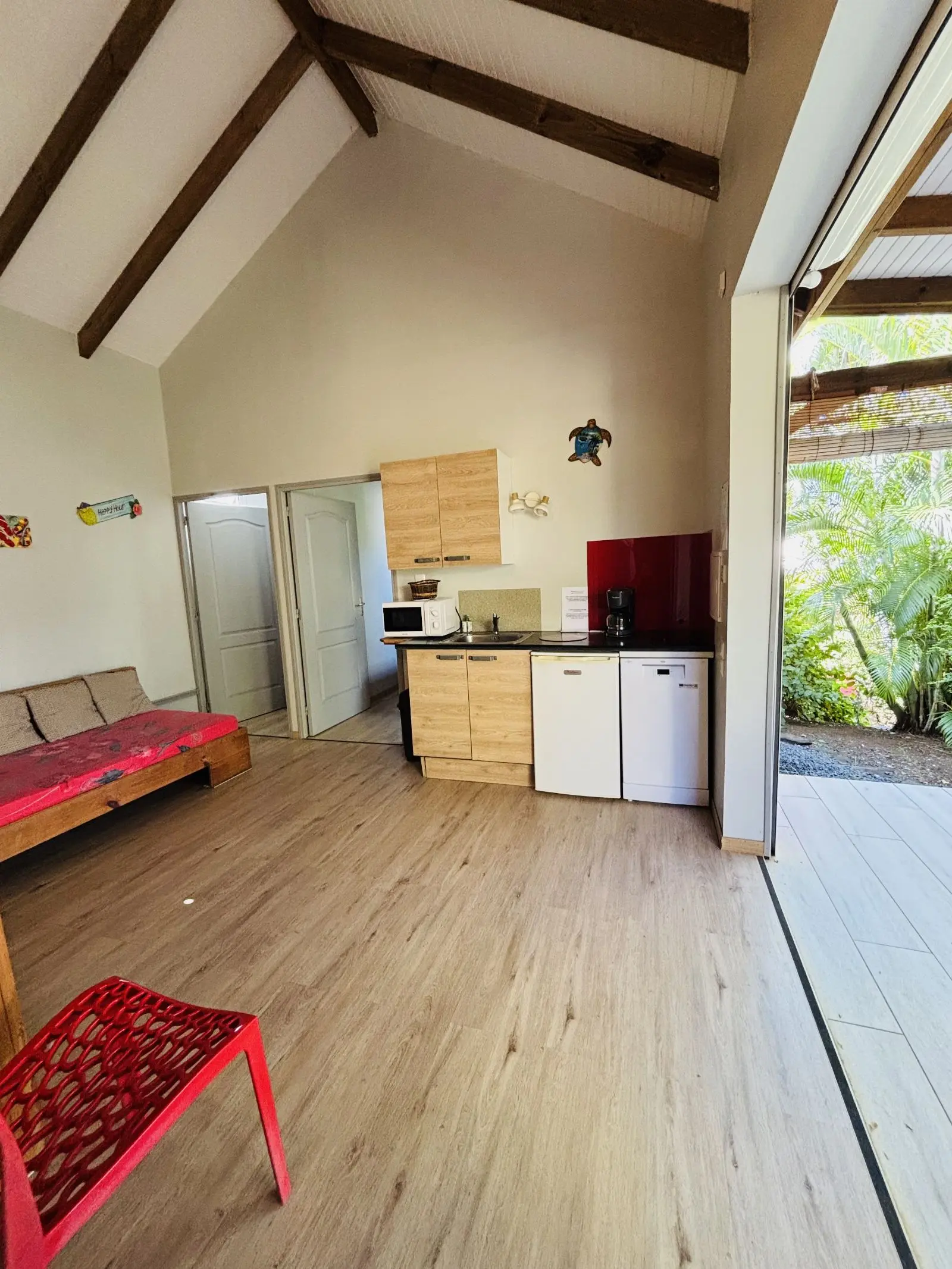 Séjour sous charpente claire, kitchenette en bois et ouverture sur la terrasse