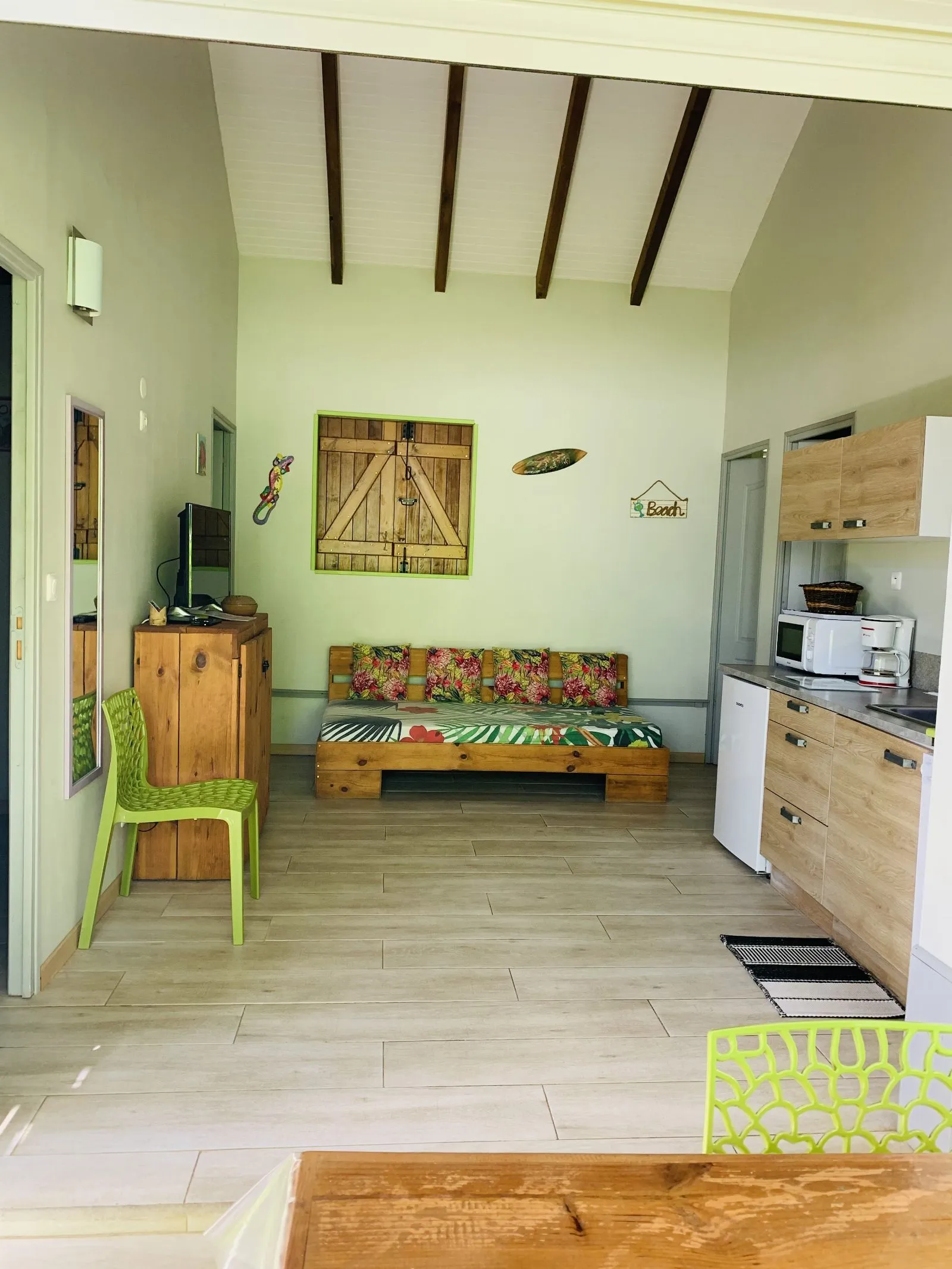 Séjour vert d’eau avec banquette à coussins tropicaux et kitchenette