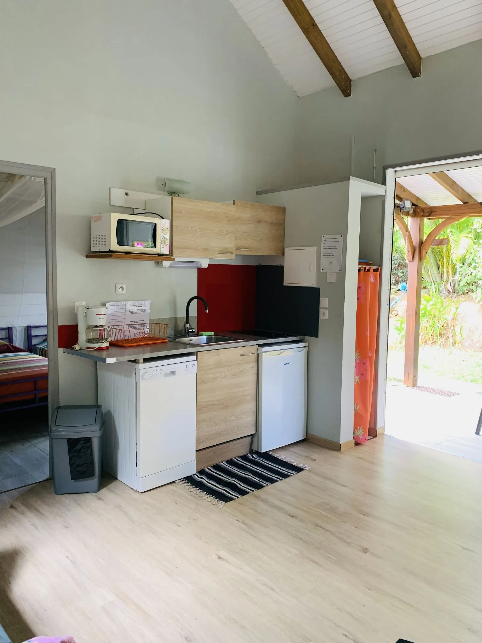 Kitchenette avec plaque, évier et réfrigérateur, ouverte sur la chambre et la terrasse
