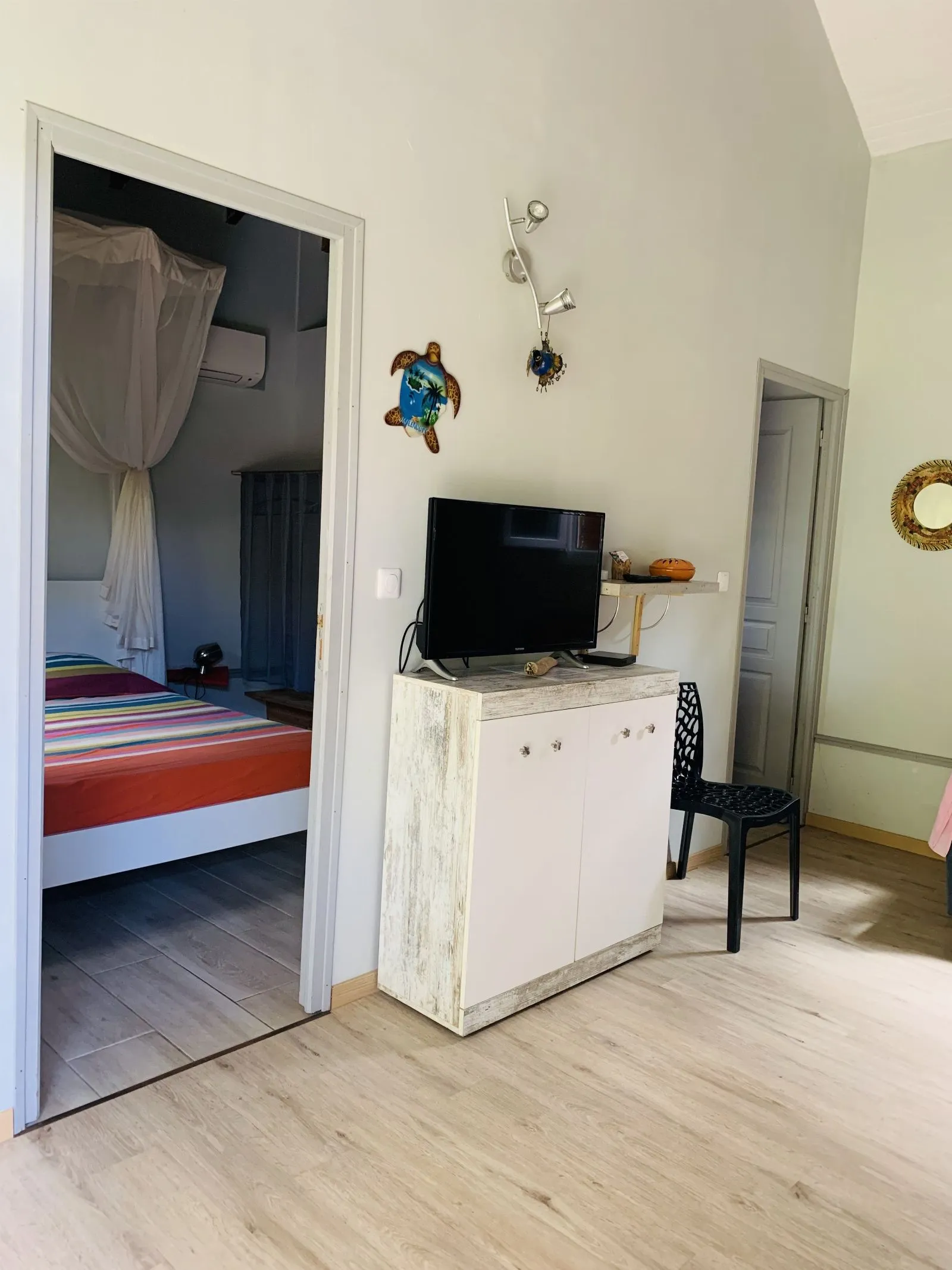 Coin télévision avec vue sur la chambre et sa moustiquaire