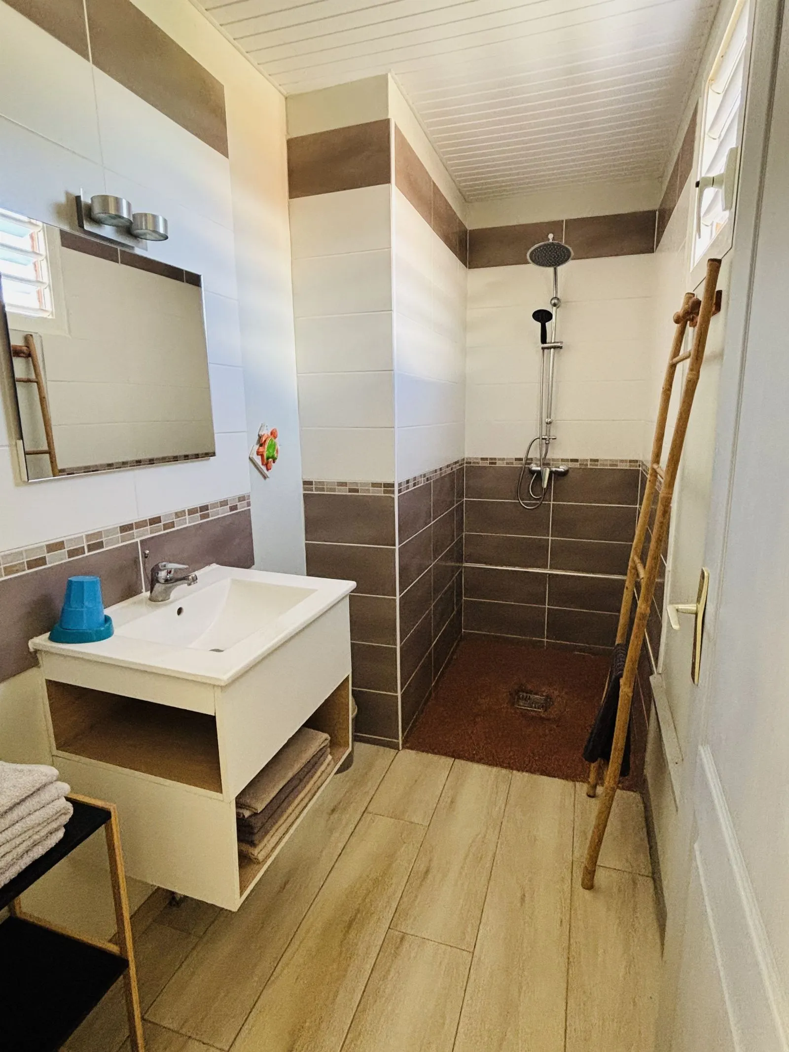 Salle d’eau carrelée avec douche à l’italienne, vasque et miroir
