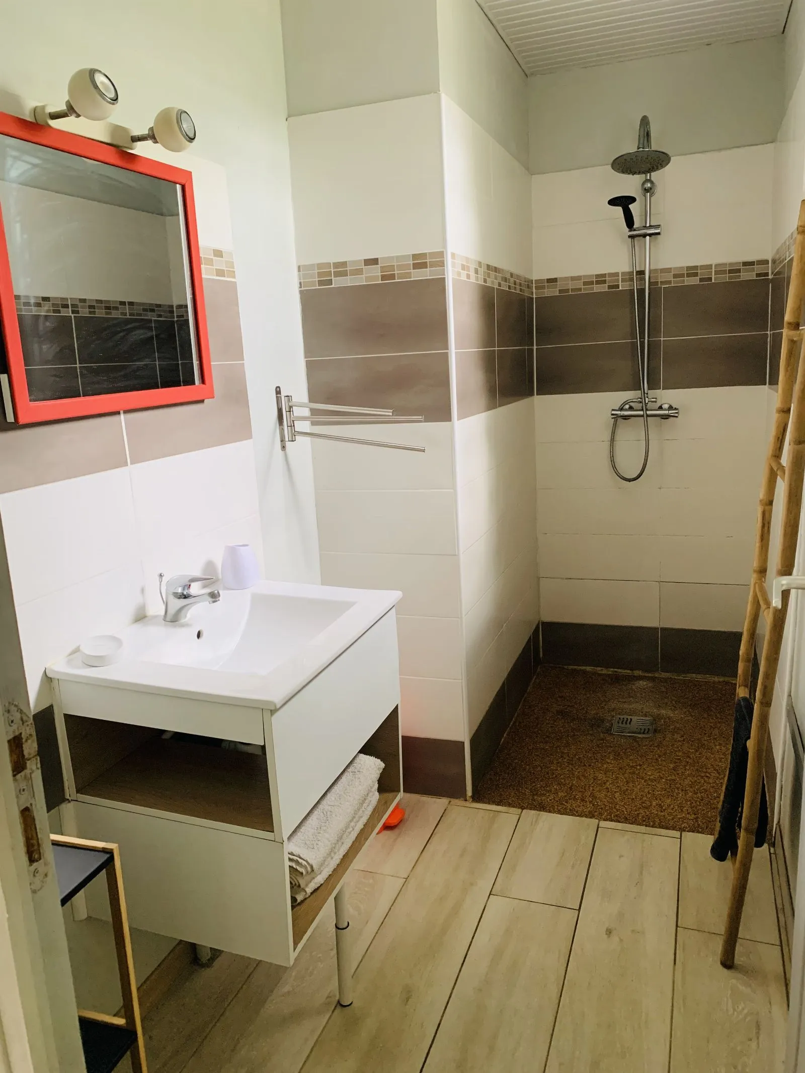 Salle d’eau avec miroir à cadre rouge, vasque et douche à l’italienne